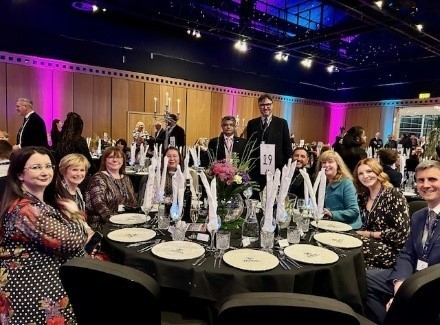 people sat at a lrage table in formal dress smiling