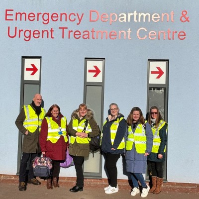 People in high vis standing outside a hospital holding vapes