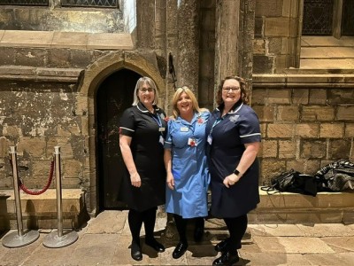 Three nurses in uniform smiling inside Durham Cathedral